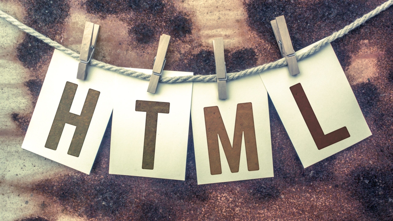 The word "HTML" stamped on cards and pinned to an old piece of twine over a rusted metal background.